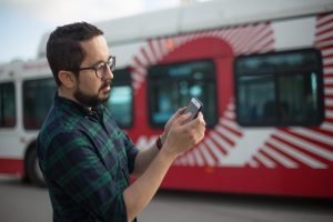 Man in front of MTS bus looking at phone 